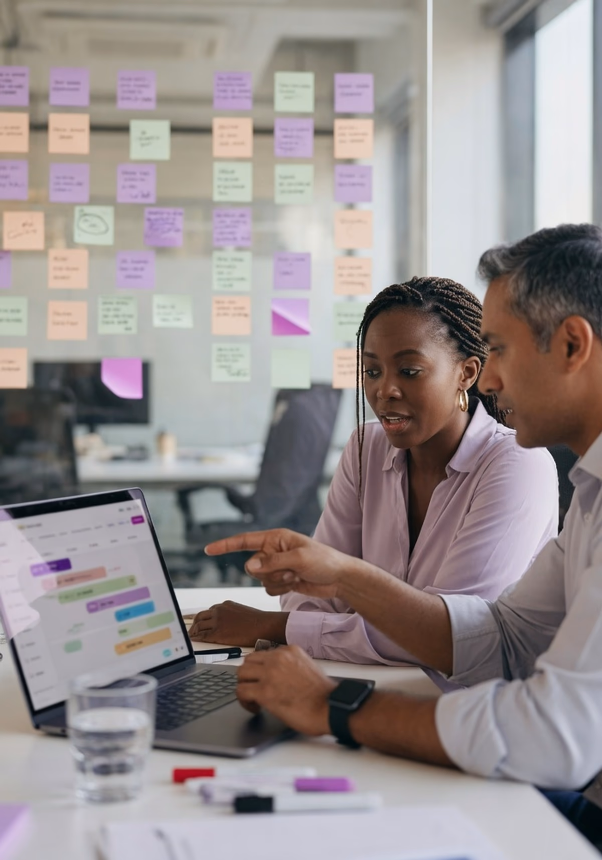 Deux consultants d'agence travaillent devant un mur de post-it