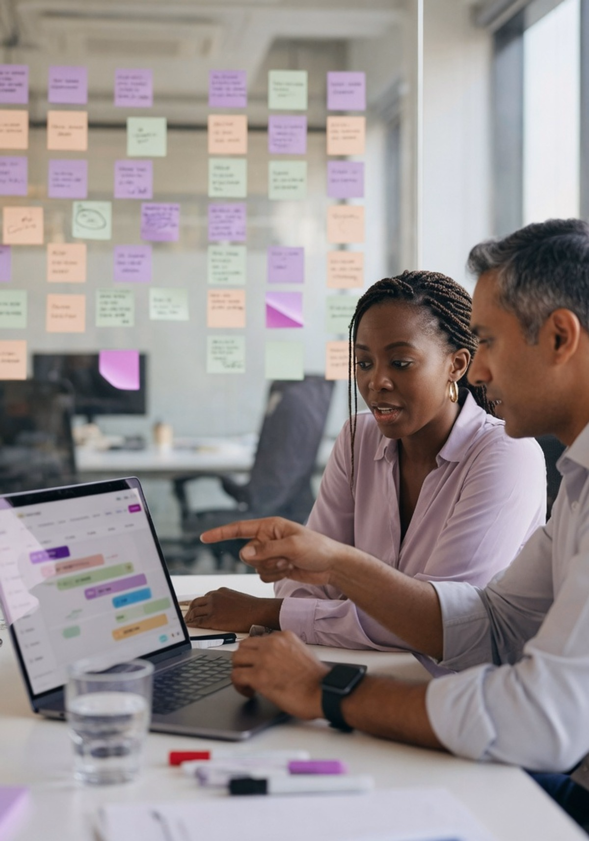 Deux consultants d'agence travaillent devant un mur de post-it