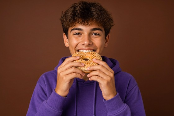 Client souriant mordant dans un bagel dans un café