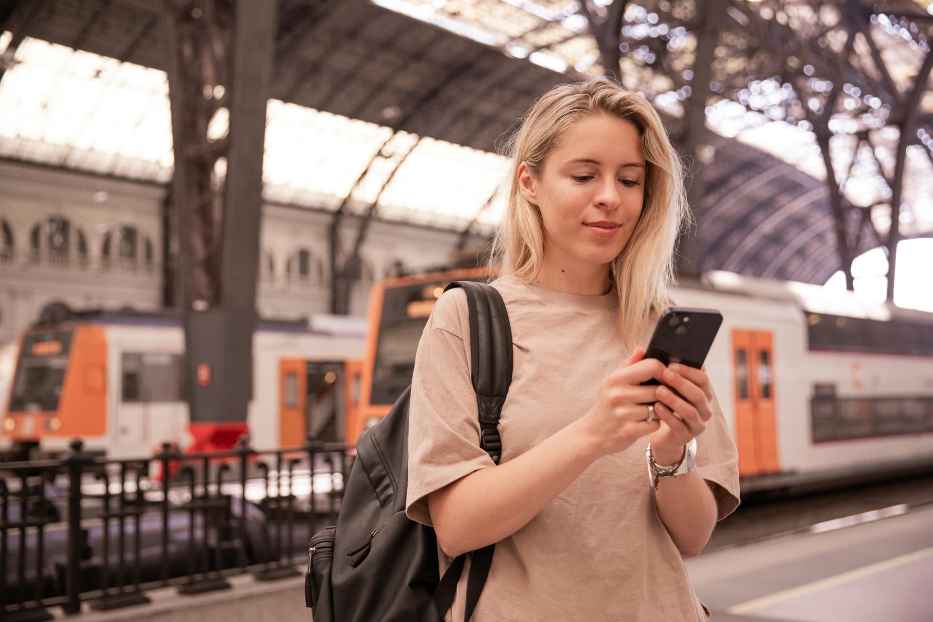 Voyageuse consultant son smartphone dans une gare, exemple de marketing mobile pour le transport
