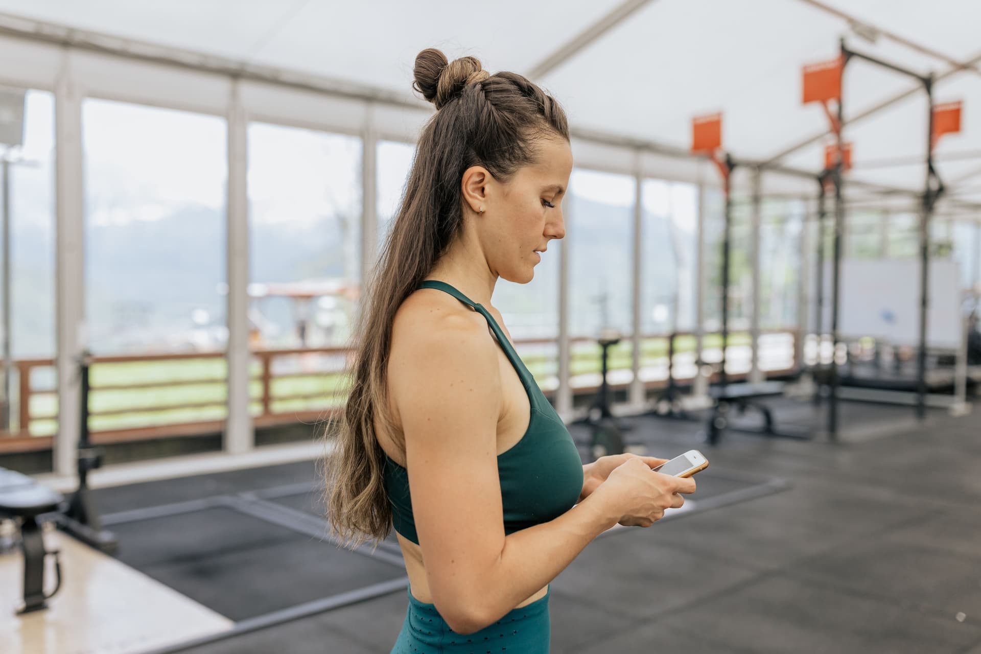 Une femme dans une salle de sport utilise son smartphone pour accéder à sa carte de fidélité digitale.
