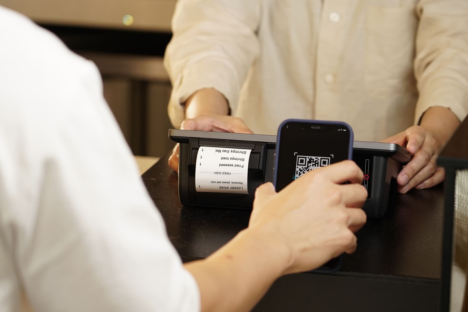 Un client scanne un QR code de fidélité sur son smartphone à la caisse d'un restaurant