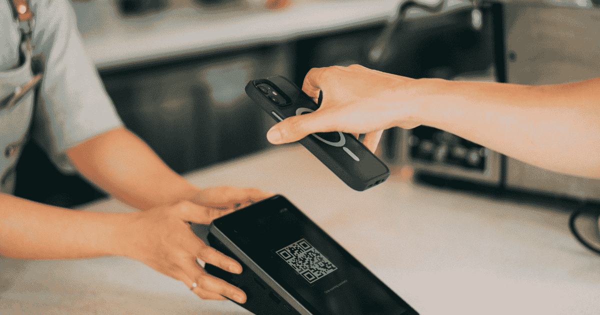 A customer uses a smartphone to scan the QR code of a digital loyalty card at a cafe checkout