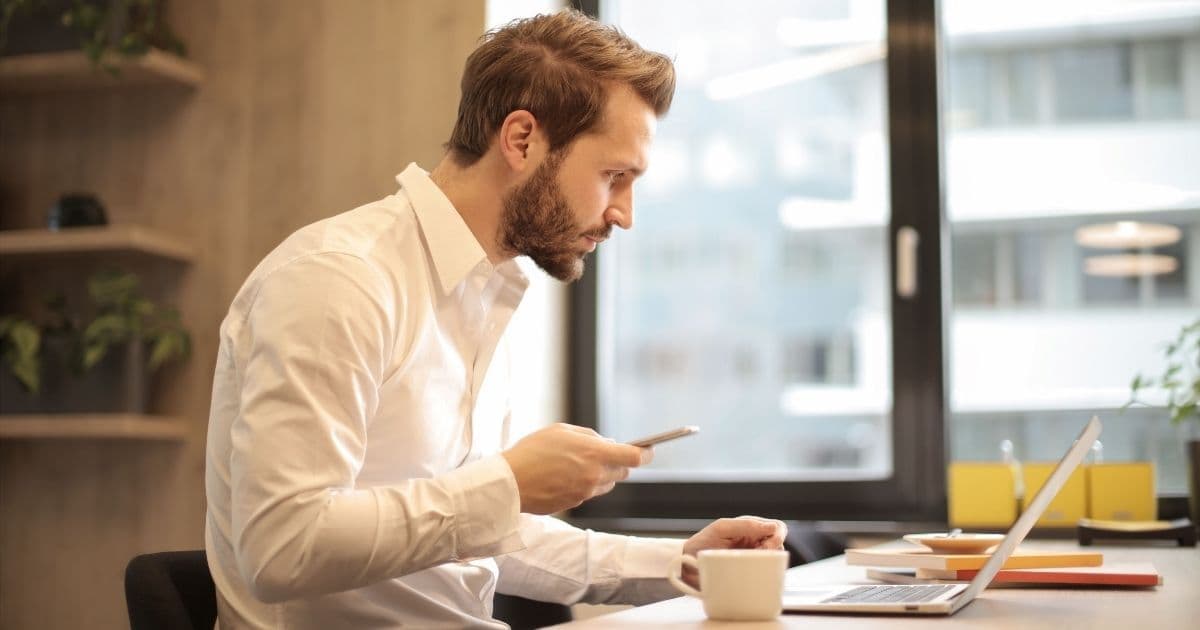 Un responsable marketing consulte son téléphone à côté de son ordinateur portable pour suivre une campagne de fidélisation wallet mobile
